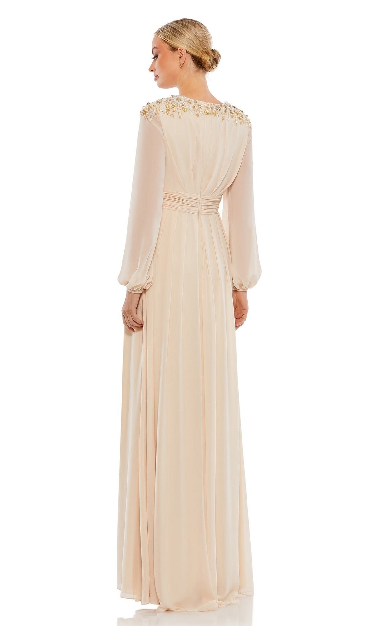 A woman in the Mac Duggal 55694 long sleeve chiffon formal dress with gold shoulder embellishments stands with her back to the camera, highlighting this elegant mother of the bride dress.